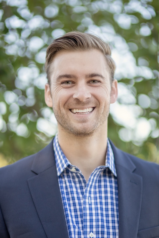 A smart man wearing checked shirt and coat, smiling at camera